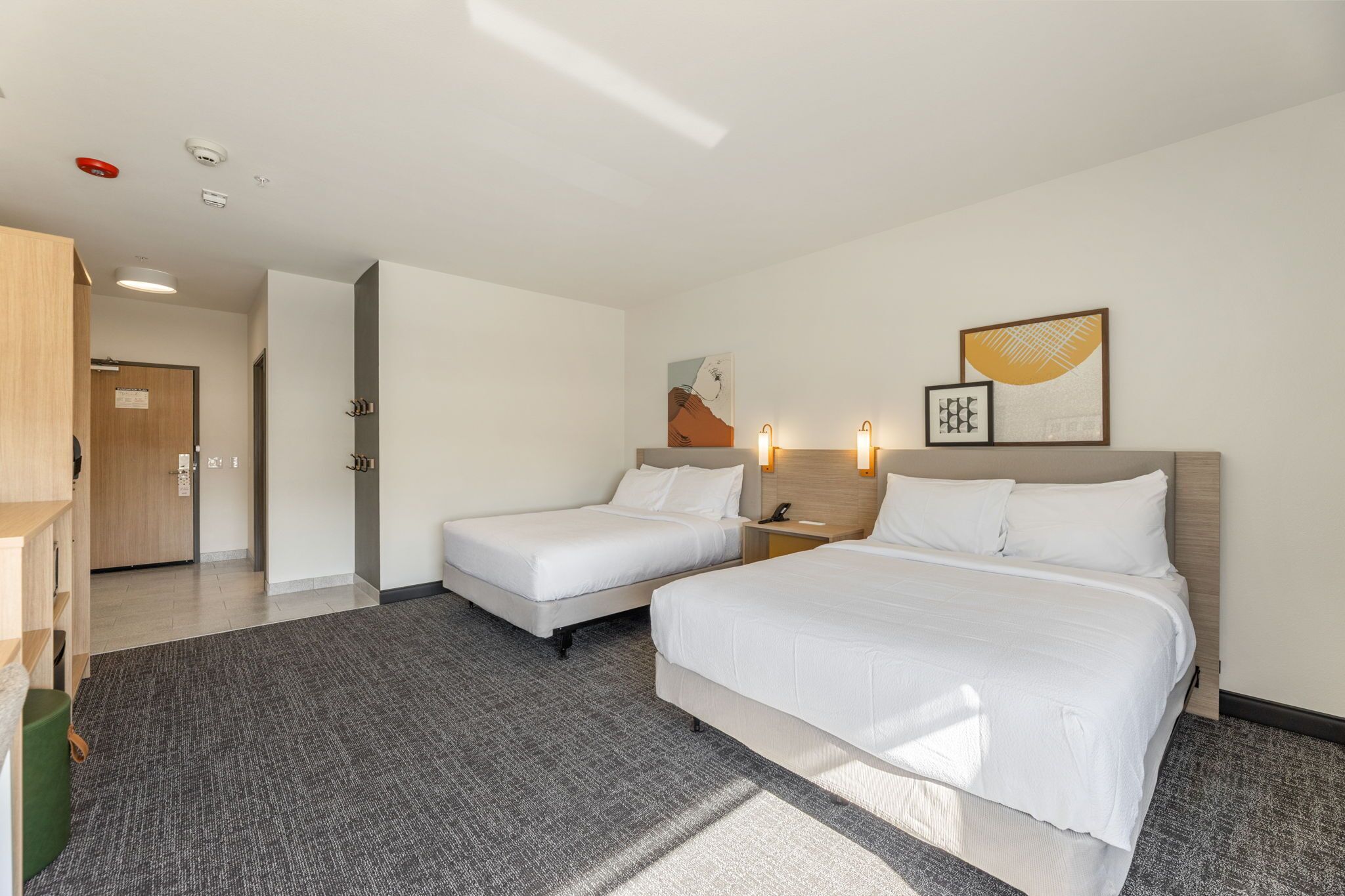 Een hotelkamer met twee bedden, een bureau, een stoel en een klein tafeltje.