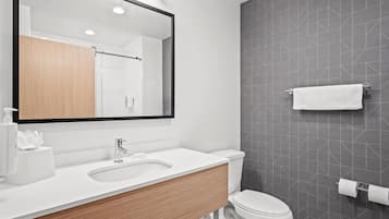 Un baño moderno con un espejo grande, un lavamanos, un inodoro y un perchero para toallas.