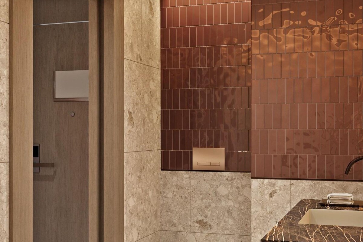 Un baño moderno con un lavamanos de mármol, una bañera y una puerta de madera.