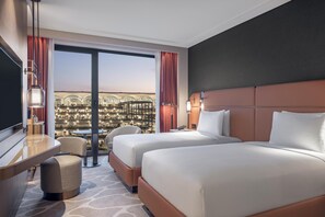 A hotel room with two beds, a desk, a chair, and a view of a cityscape. - Hilton Istanbul Airport (Arnavutköy)