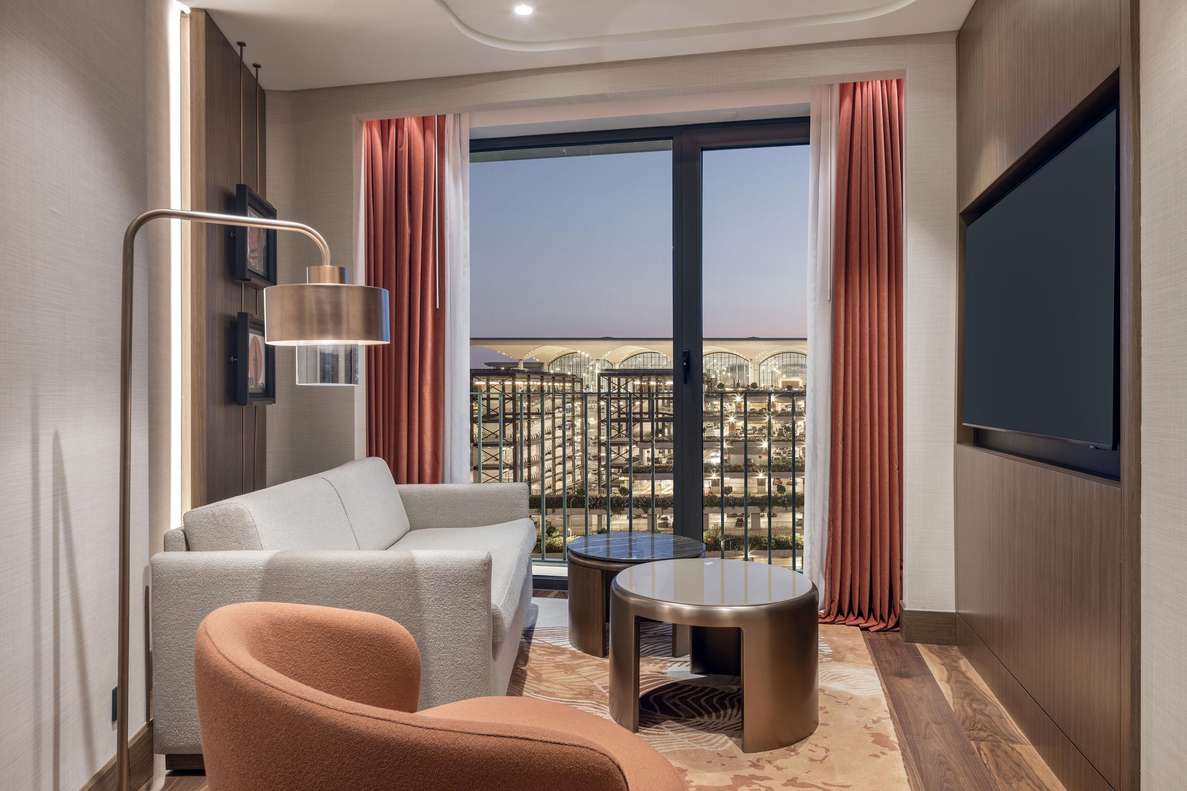 Una habitación de hotel moderna con sofá, sillón y una pequeña mesa.
