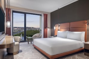Habitación de hotel con una cama grande, un escritorio, una silla y vistas al aeropuerto.