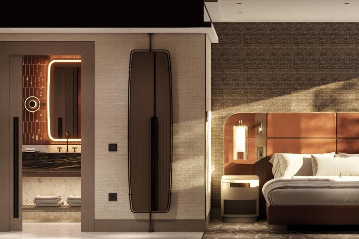 A modern hotel room with a large bed, a sitting area with a table, and a bathroom with a vanity and mirror.
