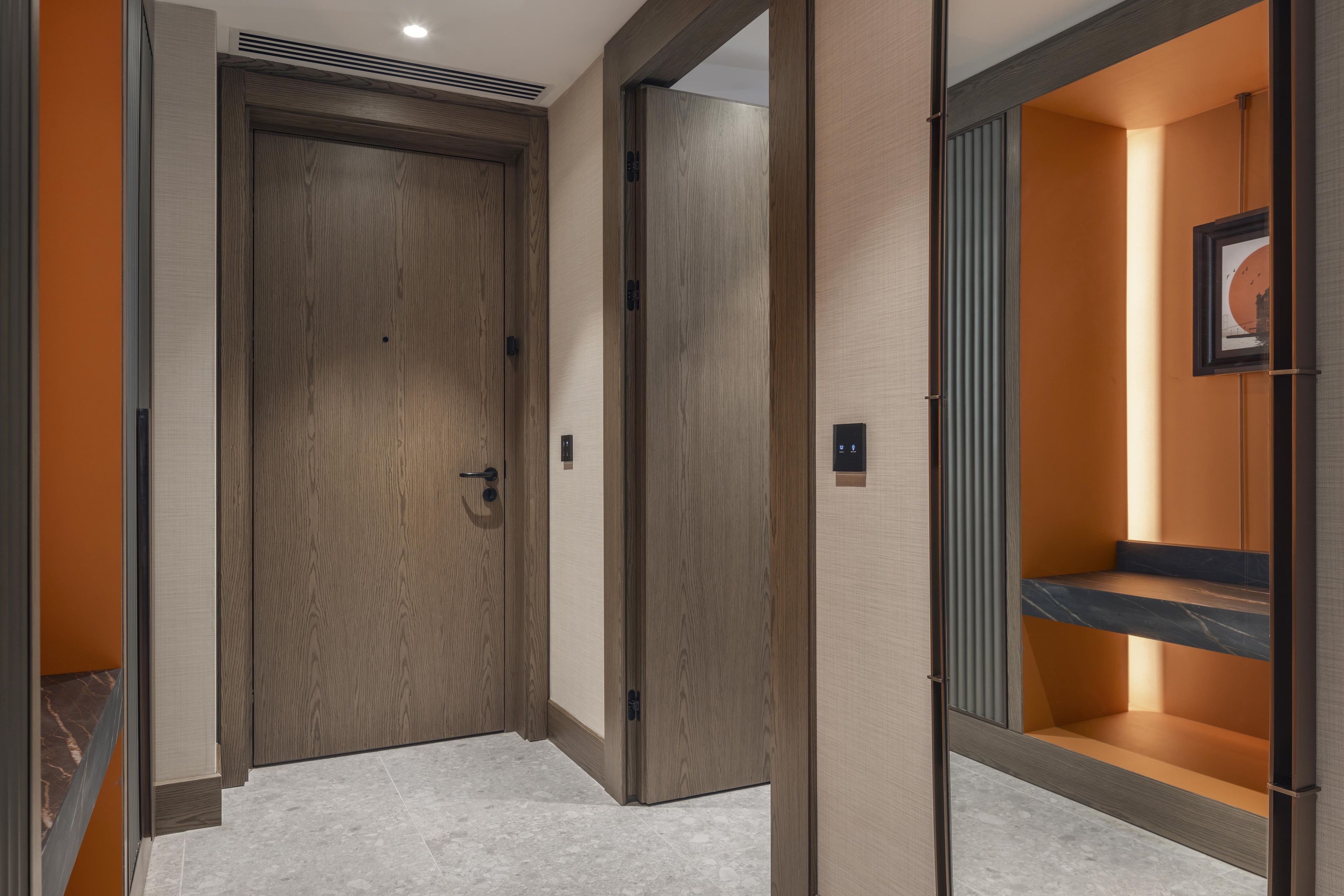 A hotel corridor with wooden doors, a tiled floor, and a framed picture on the wall.