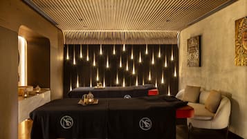 Een moderne spa ruimte met een houten plafond, een massagetafel, een massagestoel en een kunstwerk aan de muur.