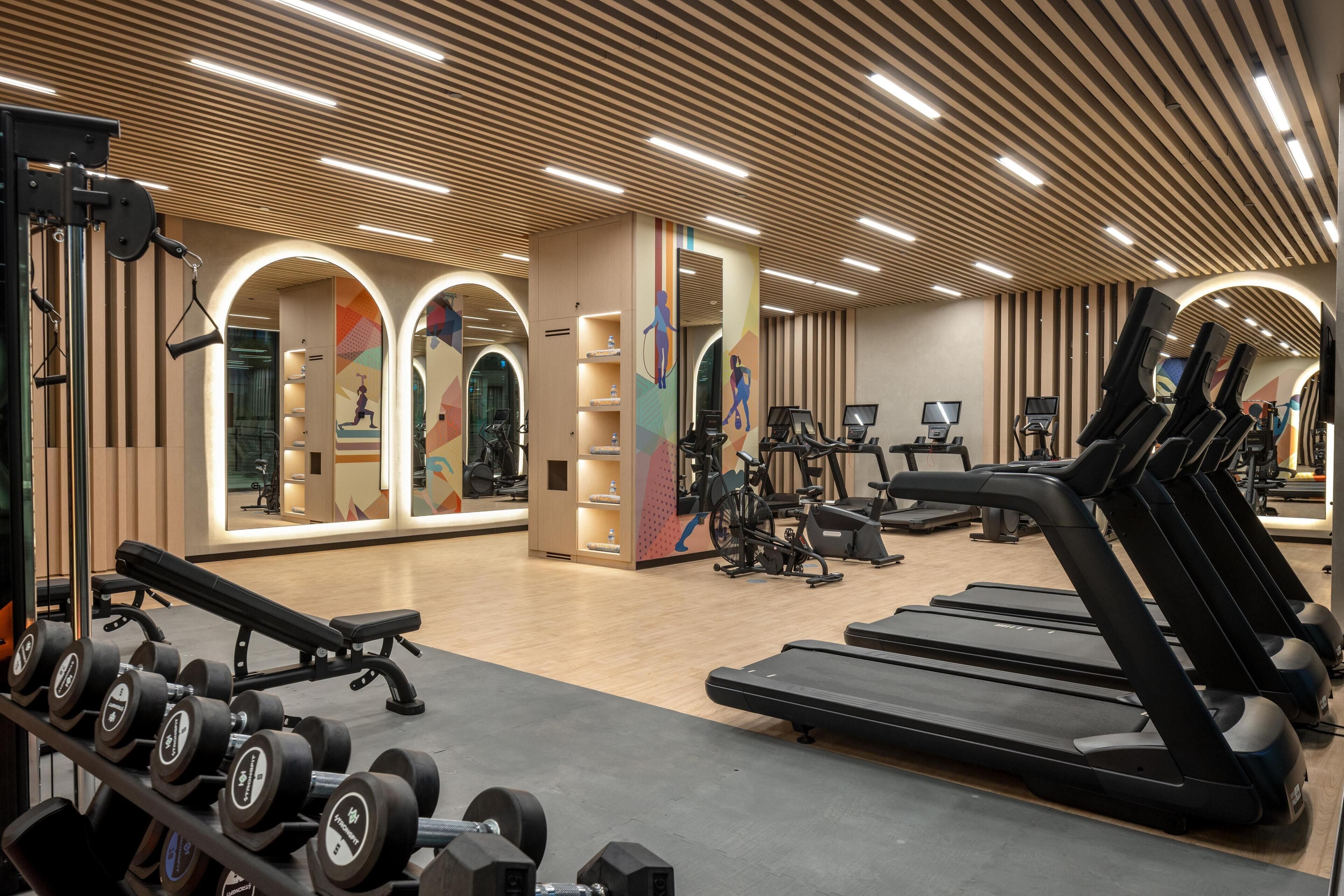 Een fitnessruimte met loopbanden, gewichten en trainingsapparatuur.
