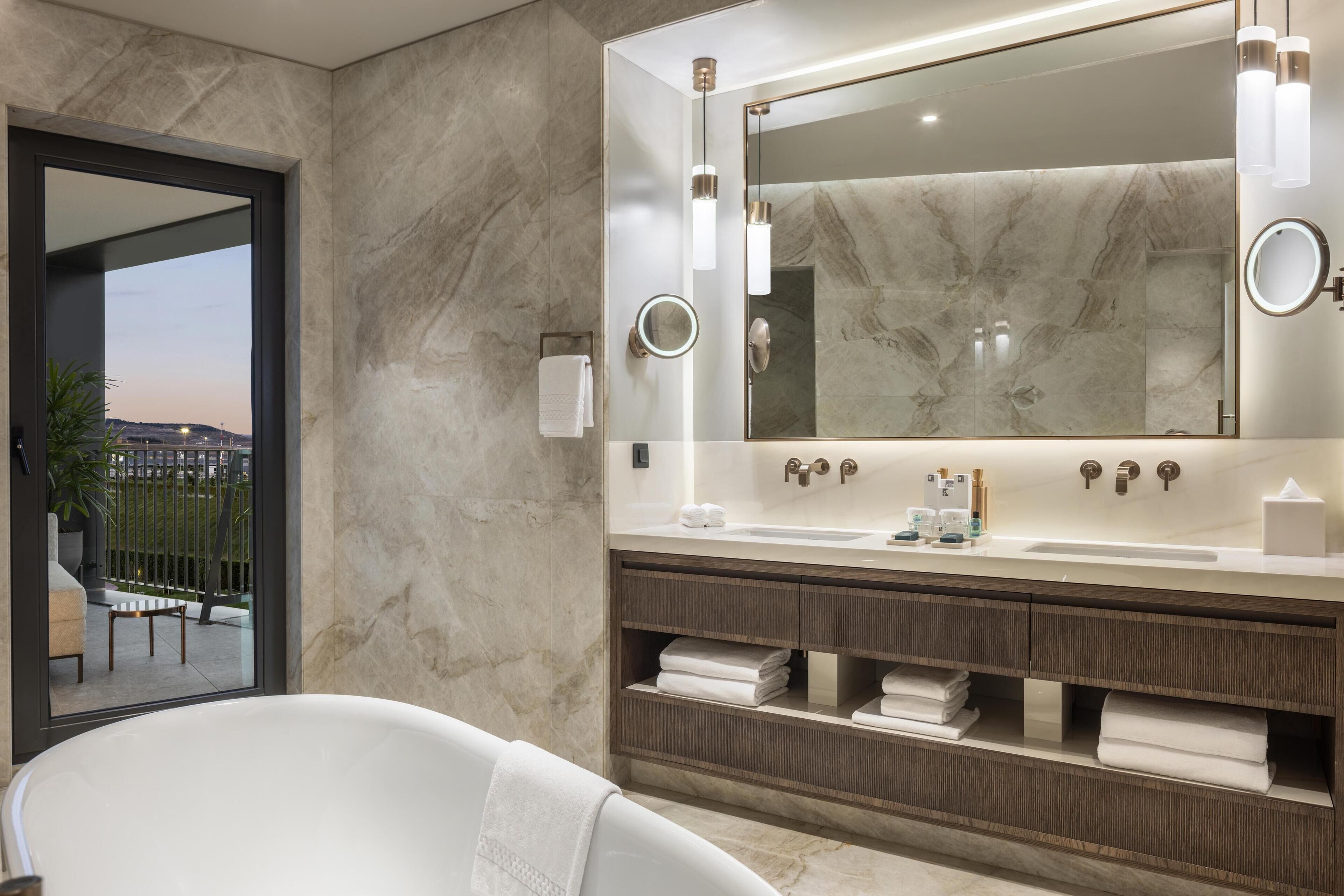 Une salle de bain moderne avec un grand miroir, deux lavabos et une baignoire.
