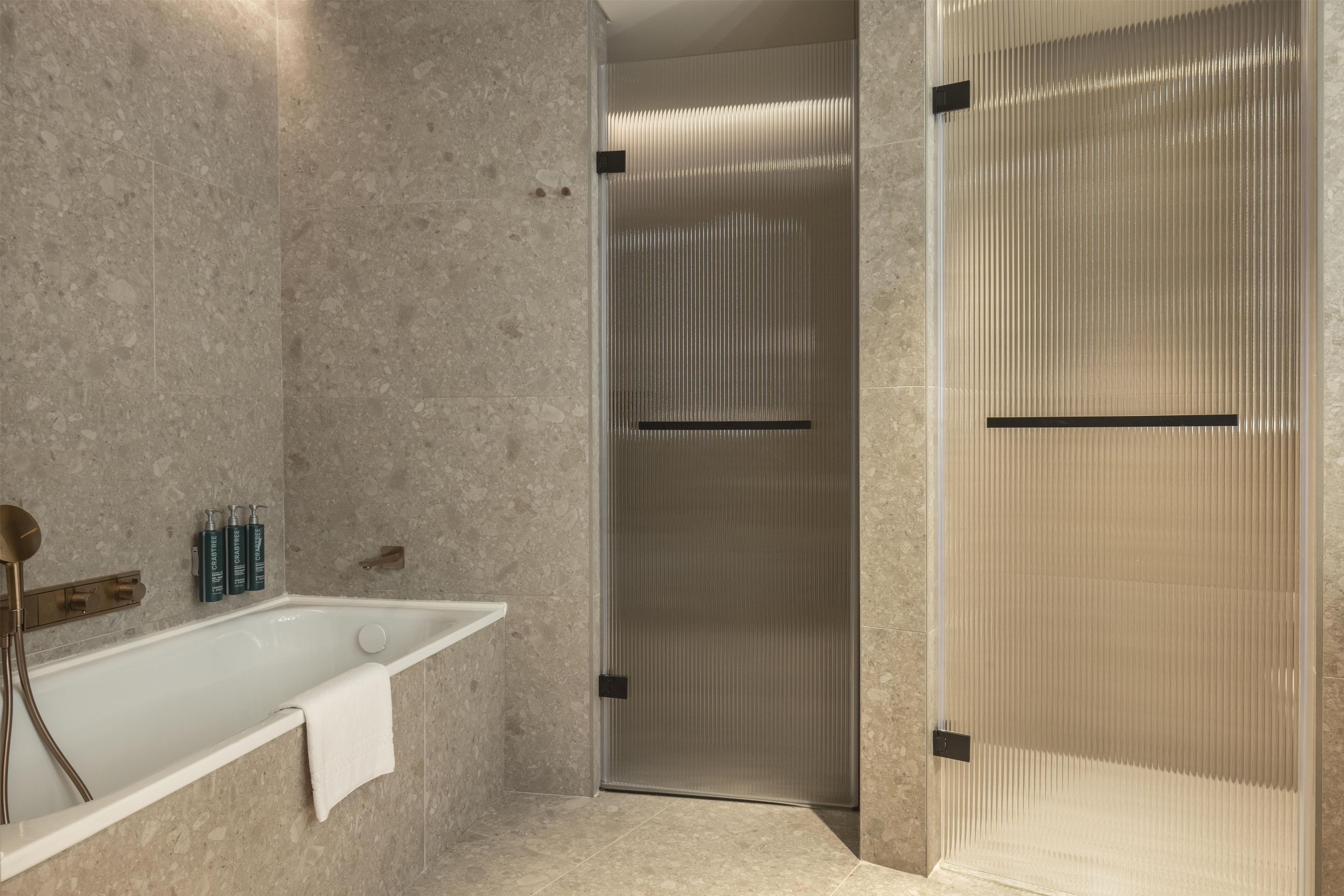 A modern bathroom with a freestanding bathtub, a shower enclosure, and a towel rack.