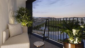 A balcony with a sofa and potted plants, overlooking a cityscape with buildings and a body of water. - Hilton Istanbul Airport (Arnavutköy)