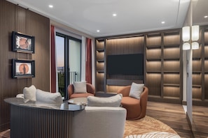 A modern living room with a sofa, chairs, a coffee table, a flat-screen TV, and framed pictures on the wall. - Hilton Istanbul Airport (Arnavutköy)