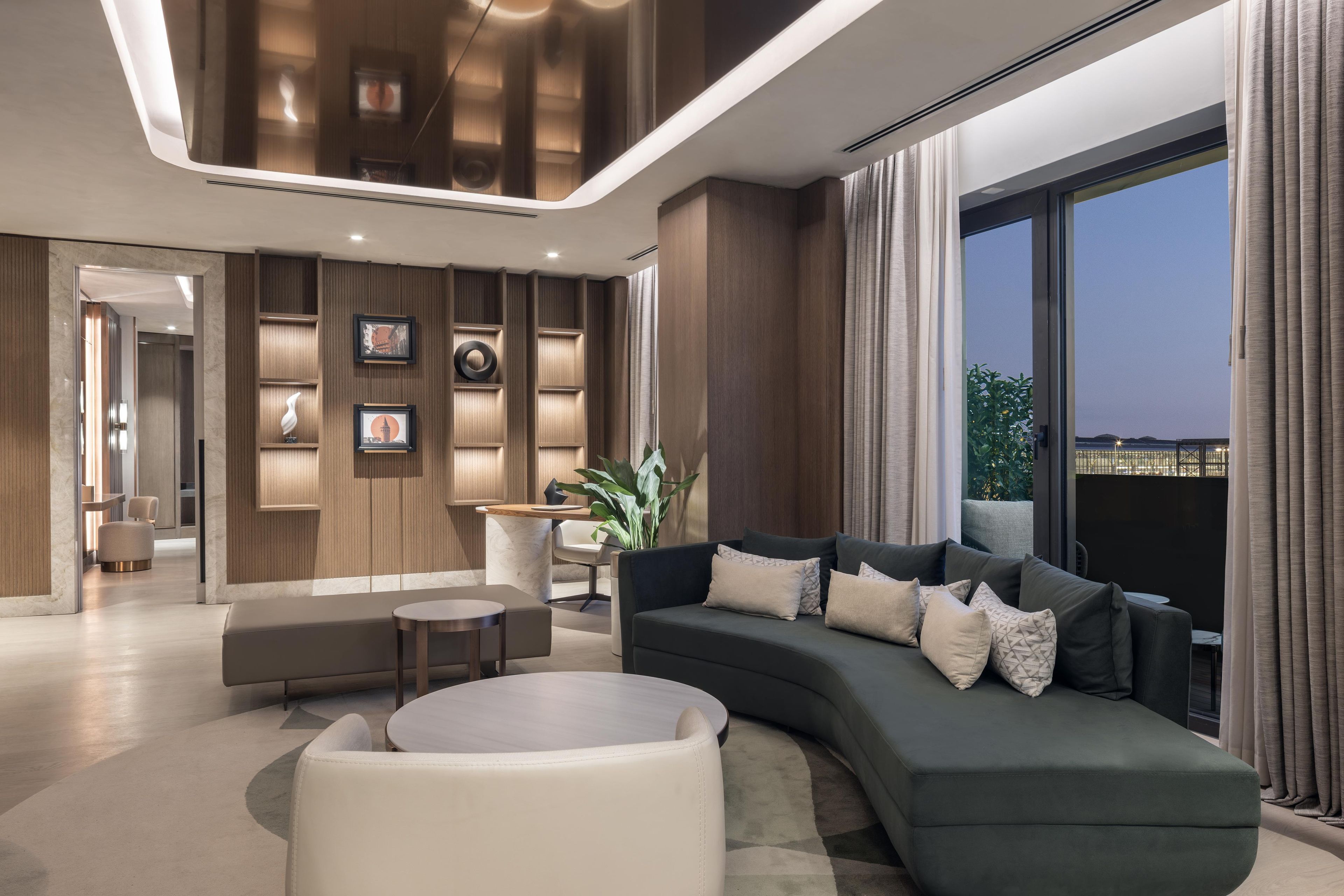 A modern living room with a curved sofa, a round coffee table, and a seating area with a small table and chairs.