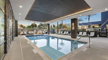Una piscina con sillas de descanso y una zona techada con techo de madera.