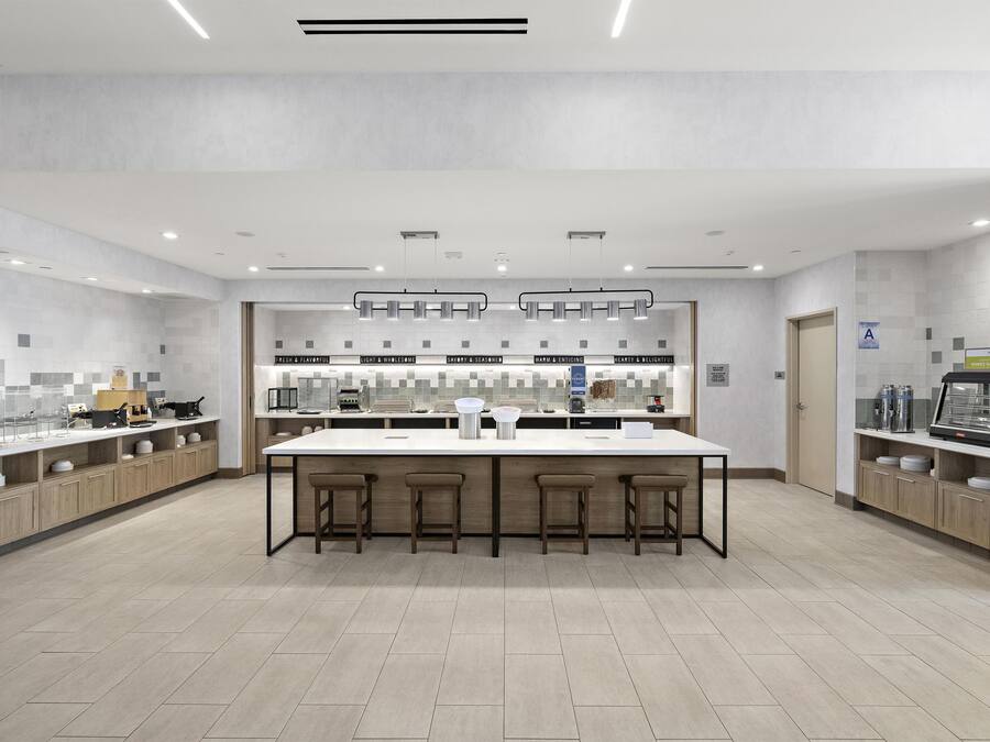 A modern kitchen with a central island, bar stools, and a variety of appliances.