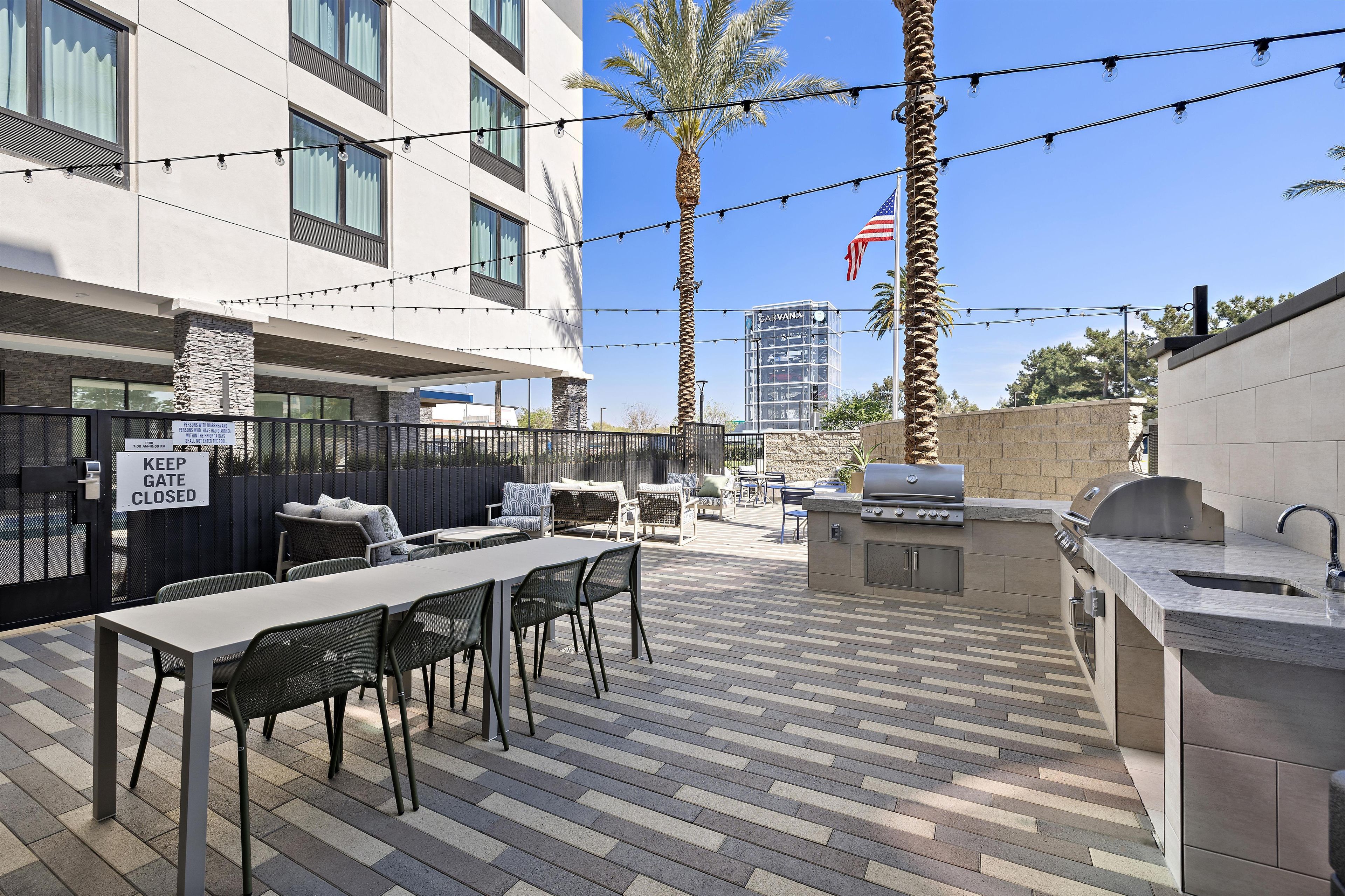 Un patio exterior con mesa, sillas y zona de barbacoa.