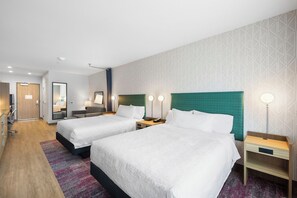 A hotel room with two beds, a desk, a chair, a mirror, and a wardrobe.