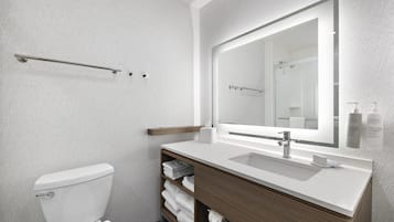 Un baño moderno con inodoro, lavamanos, espejo y toallero.