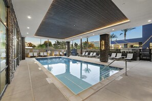 A swimming pool with lounge chairs and a covered area with a wooden ceiling. - Home2 Suites by Hilton Ontario Airport (Ontario)