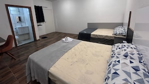 Ett hotellrum med två sängar, ett skrivbord och ett badrum som syns genom en öppen dörr.