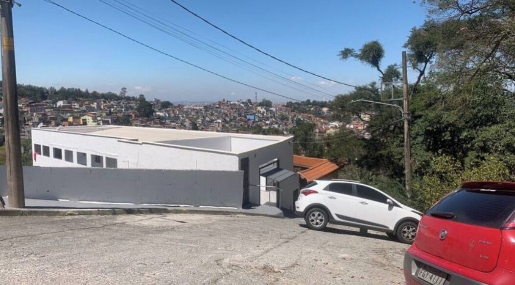 A building with a flat roof and a white facade, adjacent to a street with parked cars.