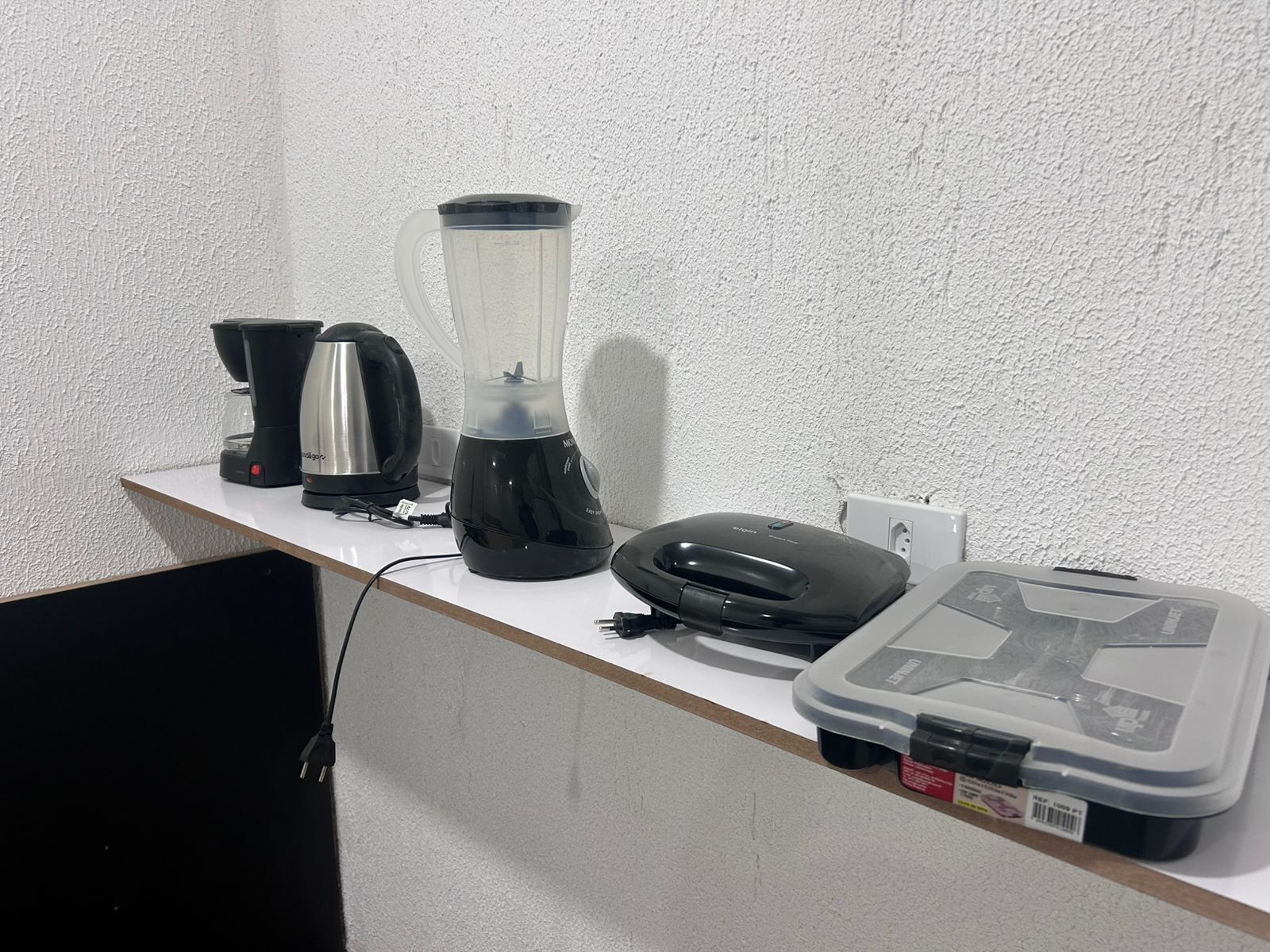 Una cuina americana amb una batedora, una cafetera i un microones damunt d'un taulell blanc.