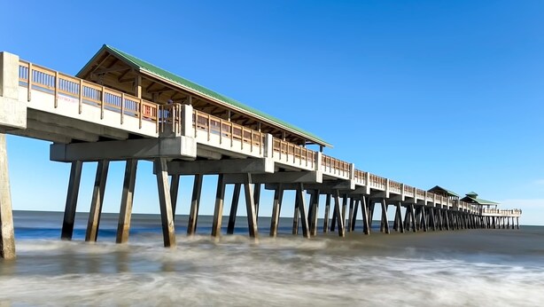 Un muelle que se adentra en el océano con una estructura techada al final.