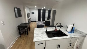 A modern kitchen with a marble countertop, white cabinets, and a black sink.