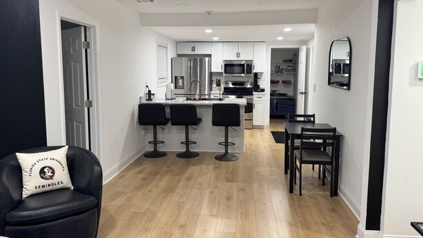 A modern kitchen with white cabinets, stainless steel appliances, and a bar area with stools.