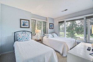Un dormitorio con dos camas, un escritorio y una ventana con persianas.