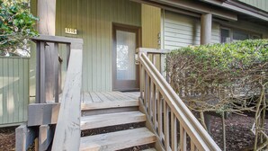 A wooden staircase with a handrail leading to a door marked '1305' on a building with wooden siding.