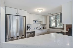 Una cocina moderna con electrodomésticos de acero inoxidable, armarios blancos y una isla grande.