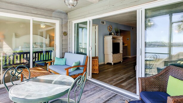 Un portico coperto con tavolo e sedie, un divano e una televisione sullo sfondo.