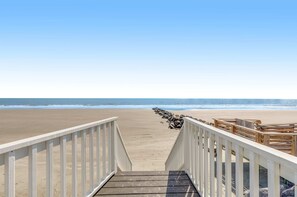 A wooden boardwalk leading to a sandy beach with a clear sky.