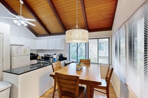 Eine moderne Küche mit weißen Schränken, einem Holzespeisetisch und einem Deckenventilator.