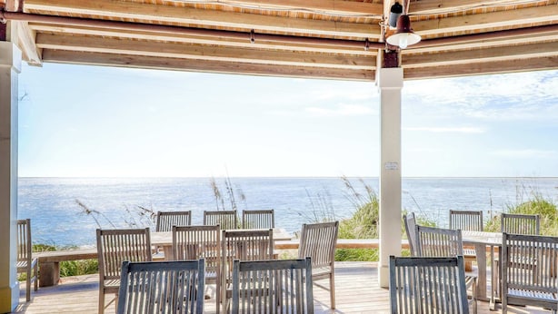 A wooden deck with outdoor seating overlooking the sea. - Comfy Golf View Cottage with WiFi, a Shared Pool, Central AC, Private Washer/Dryer (Seabrook Island)