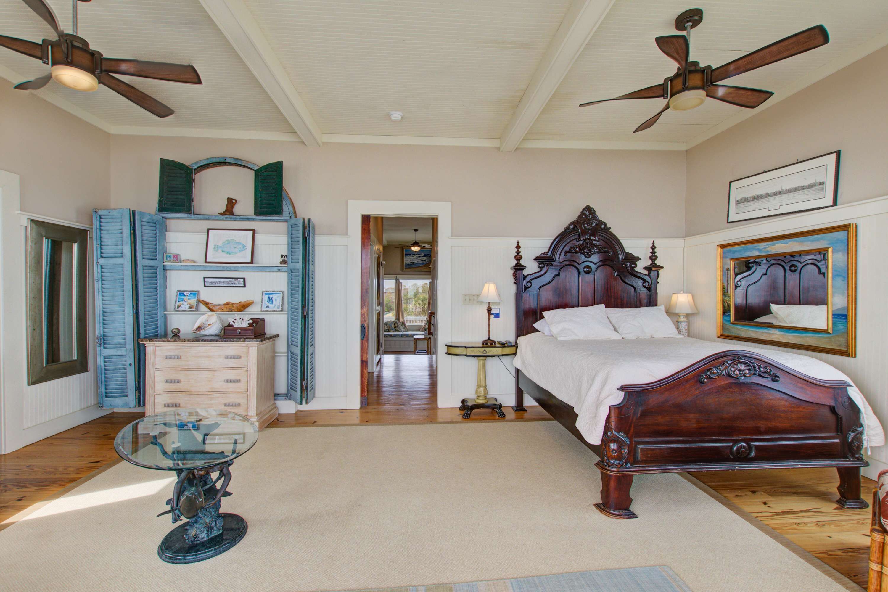A bedroom with a wooden bed, a glass table, and a ceiling fan.