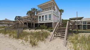 A beachfront house with a wooden deck, multiple balconies, and a staircase leading to the entrance. - Luxury, Dog-Friendly, Oceanfront Home on Folly Beach (Folly Beach)