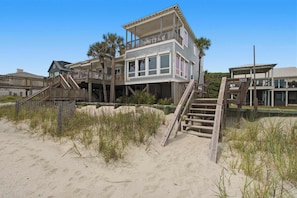 A beachfront house with a wooden deck, multiple balconies, and a staircase leading to the entrance. - Luxury, Dog-Friendly, Oceanfront Home on Folly Beach (Folly Beach)