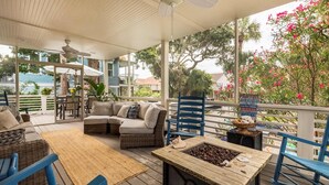 Un patio al aire libre techado con mobiliario de mimbre, una mesa de madera con chispas de chocolate y un ventilador de techo.