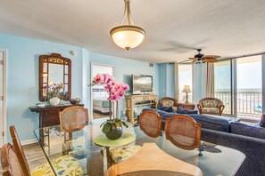 A living room with a dining table, chairs, a sofa, and a television. - Oceanfront, first-floor villa w/large balcony & shared pool - near the beach (Folly Beach)