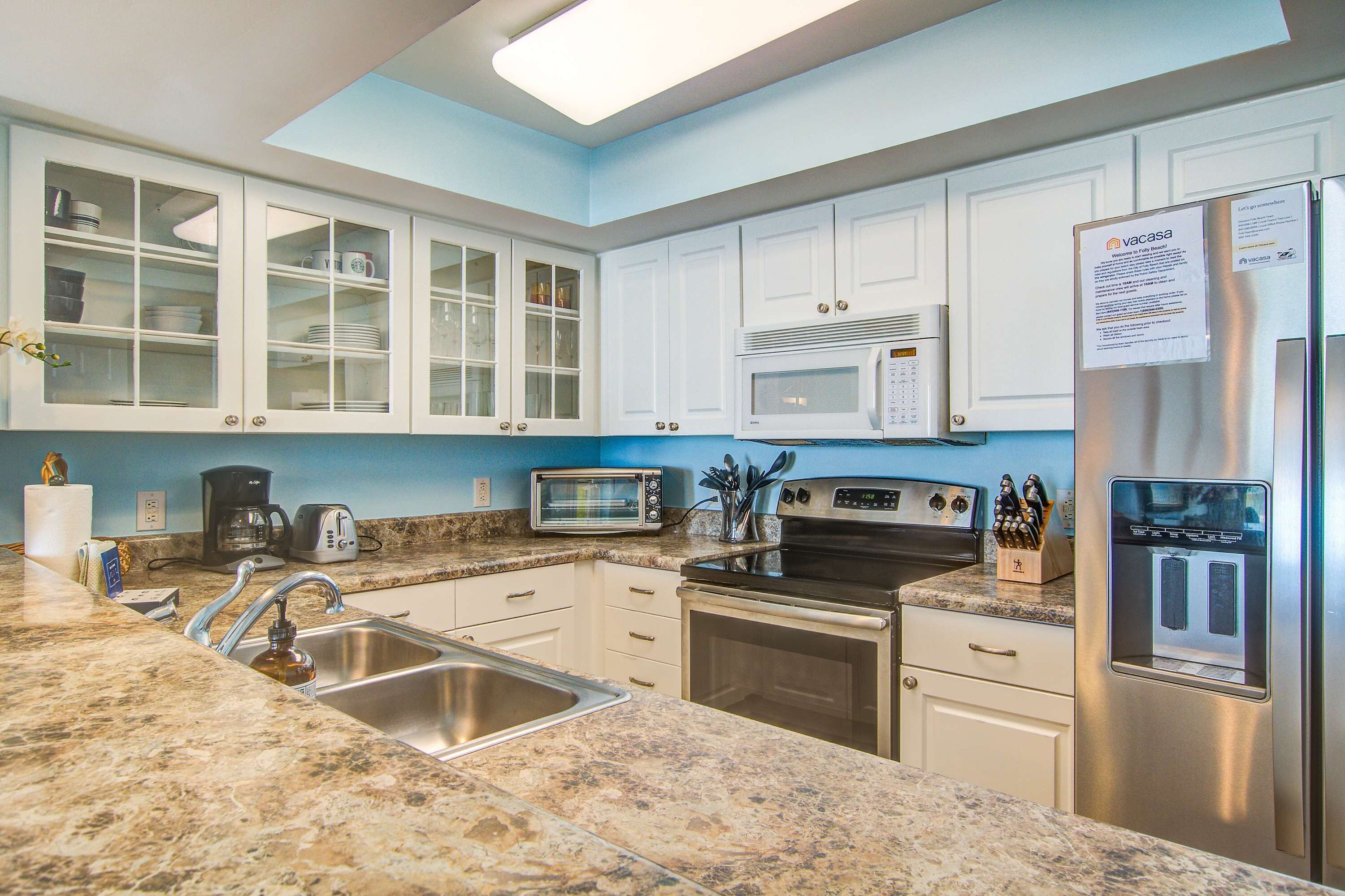 A modern kitchen with white cabinets, a stainless steel refrigerator, a microwave, and a coffee maker.