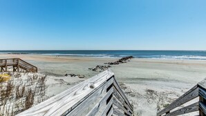 Une plage avec une promenade en bois qui mène à une zone sablonneuse.