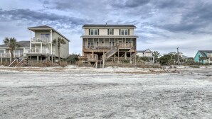 A beachfront house with a balcony, a staircase, and a view of the beach. - Raised oceanfront home with elevator & outdoor shower just steps from beach (Folly Beach)