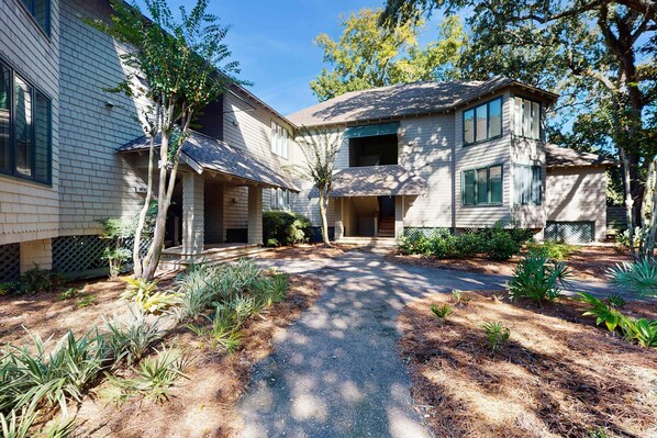 A two-story house with a covered porch and a driveway. - Lagoon-Front Villa w/ Screened Porch, WiFi & AC - Steps to Beach, Tennis & Golf (Kiawah Island)
