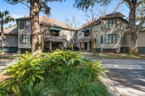 A two-story residential building with a central courtyard, surrounded by mature trees and well-maintained landscaping. - Lagoon-Front Villa w/ Screened Porch, WiFi & AC - Steps to Beach, Tennis & Golf (Kiawah Island)