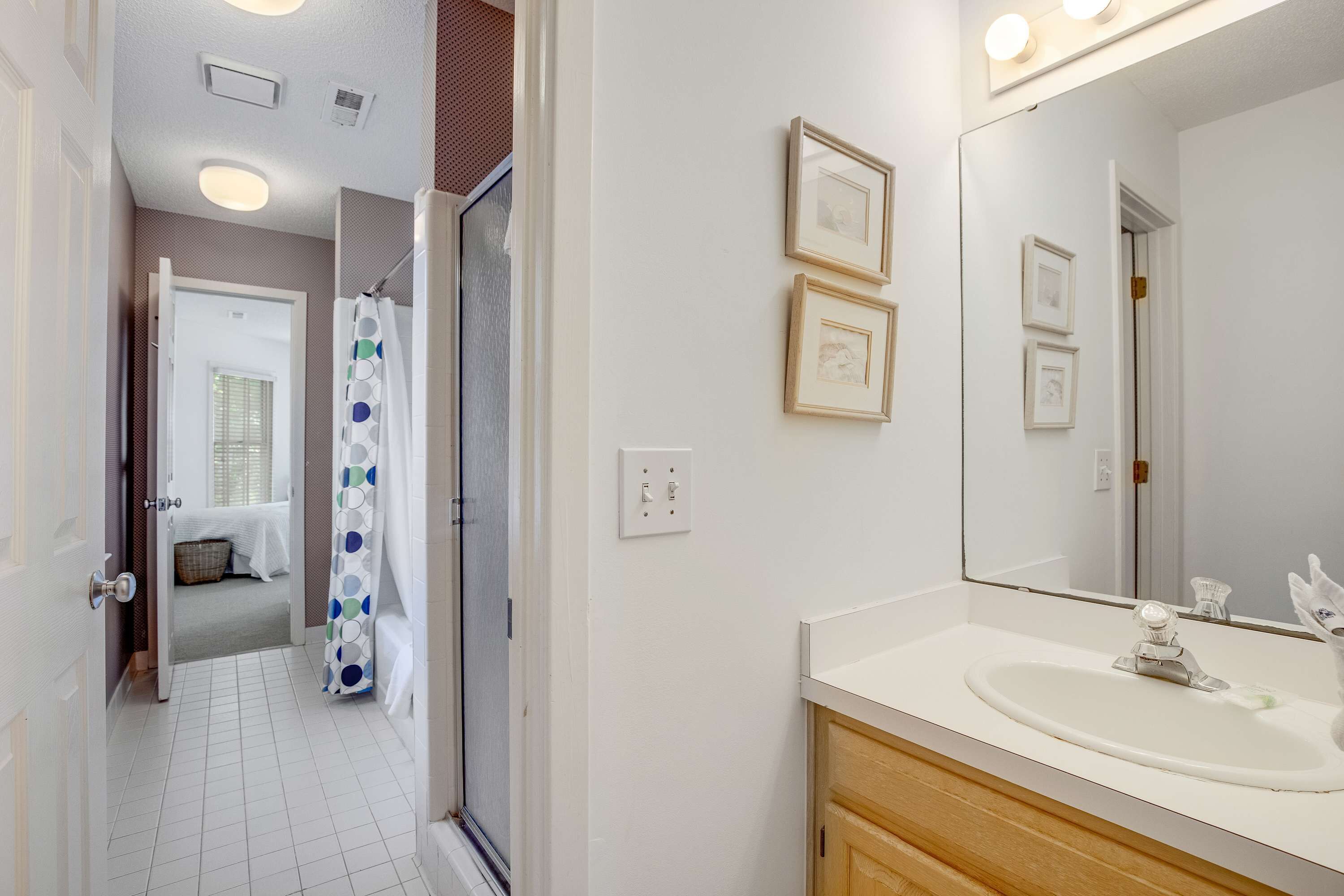 Une salle de bain avec un lavabo blanc, un miroir et un rideau de douche à motifs à pois.