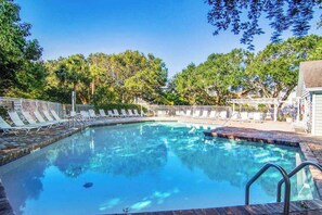 Une piscine avec des chaises longues et une terrasse en bois.
