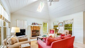 Ein gemütliches Wohnzimmer mit Kamin, einem roten Sofa, einem beigen Sessel und einem Holztisch.