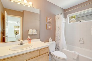 A bathroom with a white sink, toilet, and bathtub. There are two framed pictures on the wall and a window above the bathtub. - Casual cottage w/screened porch & shared pool - walk to the beach (Isle of Palms)