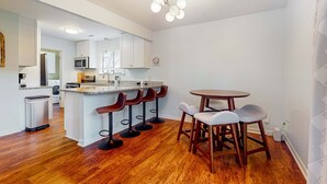 Eine moderne Küche mit weißen Schränken, einer Granit Arbeitsplatte und einer Bar mit Sitzgelegenheiten.