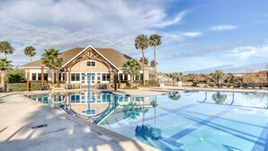 Un hotel con piscina, palmeras y cielo despejado.